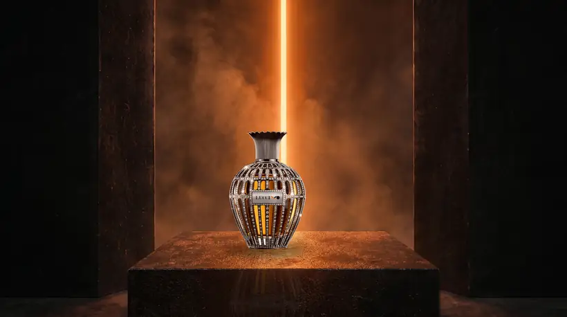 Closer view of the crystal-encrusted flacon on its plinth, lit from behind through a narrow orange slit between dark walls